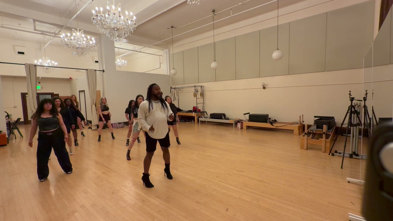 Zay leading a heels class in a chandelier studio, students in formation behind him